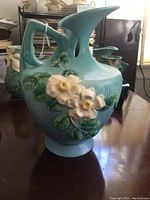 Front and side view of Roseville White Rose mold 990-10 ceramic pitcher with blue-green glaze and raised white roses decoration