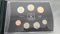Front side of specimen set showing seven Canadian coins encased in clear protective capsules, arranged in two rows of three and four with Royal Canadian Mint logo and text Specimen Set / Ensemble Specimen.
