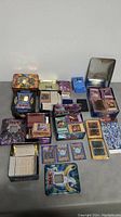 Lot overview showing multiple Yu-Gi-Oh! collectible card tins and piles of cards spread on a surface.