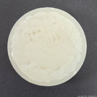 Front view of the round white jade belt buckle with carved dragon design