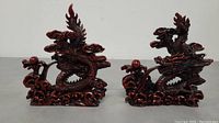 Pair of red resin Chinese dragon figurines side by side on a flat surface, showing full details and size comparison