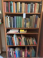 Full bookshelf showing four shelves of mostly hardback books on bird topics, used condition, variety of colors and sizes.