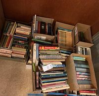 Overview of various boxes and stacks of books including vintage and encyclopedias