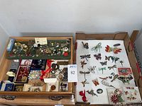 Wooden tray with divided compartments holding various pins, brooches, earrings and pendants