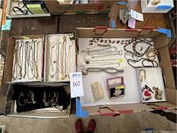 Photo showing organized collection of gold plated chains, beaded necklaces, various pendant necklaces and a vintage sterling silver floral pin in a box with other costume jewelry