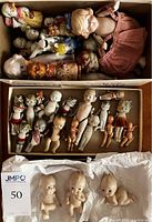 Top view showing two boxes of bisque dolls and one of ceramic Kewpie dolls all together packed in cardboard boxes.
