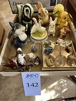Overview photo showing the full assortment of animal figurines on a table, including skunk, bunnies, ducks, geese, fox, mouse, and smaller animals on a cardboard tray.