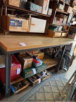 Full frontal view of the tool bench showing wood top and metal frame lower shelf with assorted boxes underneath