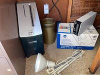 OfficeMax shredder, metal mesh trash can, Konica Minolta scanner on its box, and adjustable shop lamp all shown together