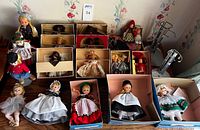 Overview of multiple small vintage dolls mostly in original boxes, including dolls in traditional clothing and original packaging.