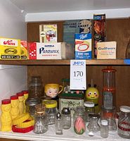 Full view of vintage kitchen items on shelf including wax boxes, jars, salt box, and vintage bottles and containers.