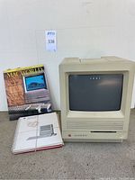Front view of Macintosh SE/30 computer with owner's guide and MacWorld magazine.