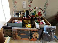 Wide view showing assortment of vintage toys including wooden blocks, books, and toy containers on table.