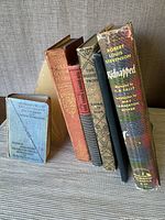 Front view of the bookends holding the stack of seven antique books with visible spines.
