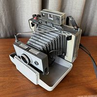 Front side view of the Polaroid 230 Land Camera showing the extended bellows, lens, and fold-out base.