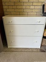 Full view of white dresser showing three drawers and simple cube-shaped handles.