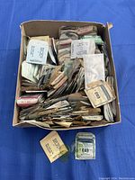 Photo of a box filled with numerous envelopes, each containing watch crystals in assorted sizes. Some envelopes yellowed with age.