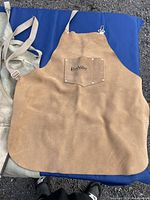 Three aprons laid out for display, showing the brown Lee Valley apron on top of two large canvas aprons underneath.