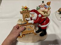 Porcelain figurine front view showing Santa placing cookies on cabinet and bag of toys