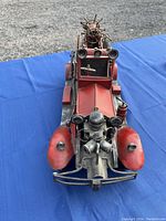 Front view of red metal vintage fire truck showing headlights, grille, and front details.