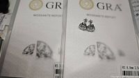Pair of moissanite stud earrings in silver-tone setting on a GRA Moissanite Report certificate.
