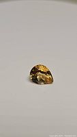Photo of pear cut golden citrine gemstone, showing the faceted cut, rich honey-yellow color, and clarity.