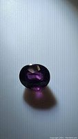 Photo of oval cut deep purple Spinel gemstone showing its rich color and internal reflections.