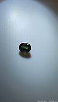 Photo of the natural green sapphire oval cut gemstone showing deep green color and some internal inclusions.