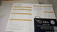 GRA certificate and grading report showing 2 carat round cut moissanite, VVS1 clarity, D color, with certificate and warranty card pairing to the ring.