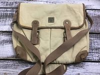 Full front view of the beige heavy canvas shoulder bag with brown leather details, showing strap and two front pockets.