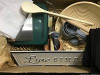 White metal box labeled 'Live Simple' containing baking utensils and tools.
