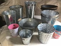 Front view of 12 assorted metal and decorative containers for plants or flowers.