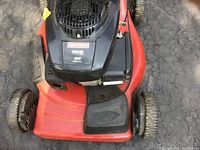 Top-down view showing black Kohler Courage engine cover labeled with Craftsman brand and red mower deck with some wear.