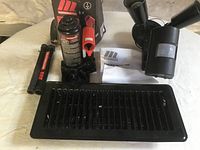 Motomaster 2 ton bottle jack in original box, black air vent cover, and black motion detector on a white cloth surface.