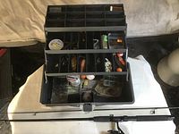 Opened Old Pal 3 tray tackle box showing multiple compartments with fishing tackle and accessories inside, black plastic box.