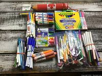 Top view of the box showing Crayola markers, pens bundled by color, and crayons including large flashlight shaped crayon.