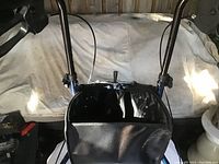 Close up photo showing the front handle and black storage pouch attached to rollator frame