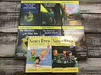 Photo showing all eight Nancy Drew books in the lot, including volumes 4, 5, 6 and others along with two Clue Books with cartoon covers.