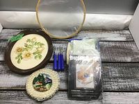 Full lot contents including framed needlepoint piece, small needlepoint decoration, embroidery hoop, latch hook tools, and needlepoint kit.