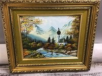 Full frontal view of the painting in ornate frame showing mountains, church, river, trees.