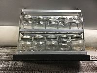 Front view of metal spice rack holding 10 glass jars, showing two shelves and black base