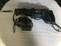 Photo showing black and blue Rona reciprocating saw with power cord, laid on white cloth.