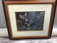 Framed print showing hummingbirds and pink flowers with natural rocky background.
