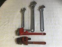 Front view of 5 wrenches laid flat on a light-colored surface, showing their sizes and condition.