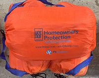 Orange bag containing flood barrier components with HSF Homeowners Protection and FB Systems branding.