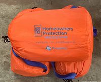 Orange FB Systems flood barrier bag with blue handles and Homeowners Protection Spill & Flood Package branding.