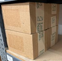 Four stacked cardboard boxes labeled Lazarus Naturals, each containing multiple bottles of hand sanitizer spray.