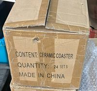 Photo of the cardboard shipping box showing 'Content: Ceramic Coaster, Quantity: 24 Sets, Made in China' label.
