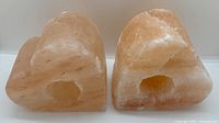 Two heart-shaped Himalayan salt candle holders shown at an angle. Display the natural crystalline orange/pink salt texture and the single hole for a candle.