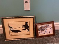 Two framed prints displayed side by side: left is the Henry Napartuk Eskimo and beluga print; right is the small Keirstead hockey scene print.